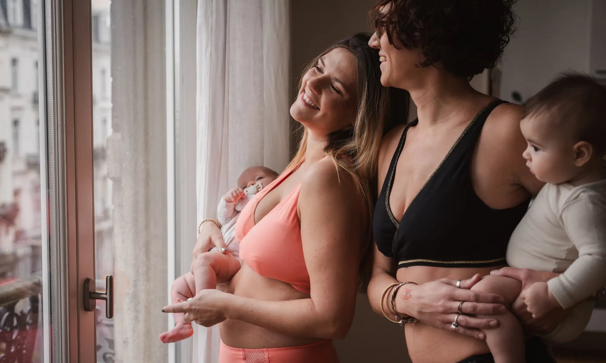 deux mamans avec bébés souriantes en brassière d'allaitement rose et noire